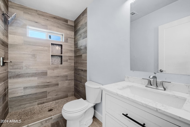 bathroom featuring tiled shower, hardwood / wood-style floors, vanity, and toilet