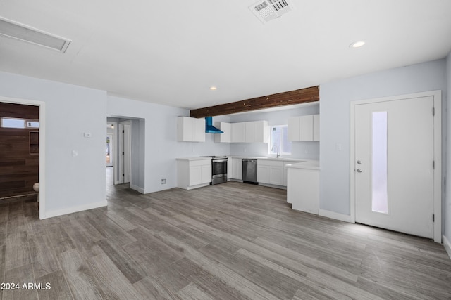 kitchen with beam ceiling, wall chimney exhaust hood, light hardwood / wood-style flooring, white cabinets, and appliances with stainless steel finishes