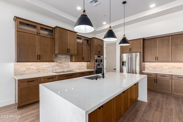 kitchen featuring sink, stainless steel fridge with ice dispenser, an island with sink, wood-type flooring, and decorative light fixtures