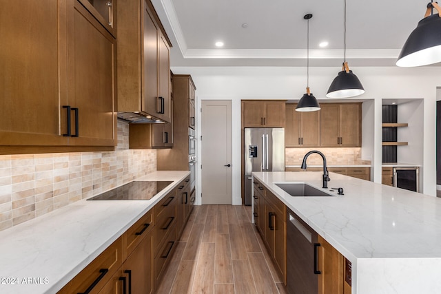 kitchen with light stone countertops, sink, light hardwood / wood-style floors, pendant lighting, and appliances with stainless steel finishes