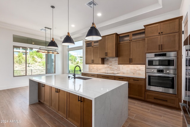 kitchen featuring decorative light fixtures, wood-type flooring, stainless steel double oven, and sink