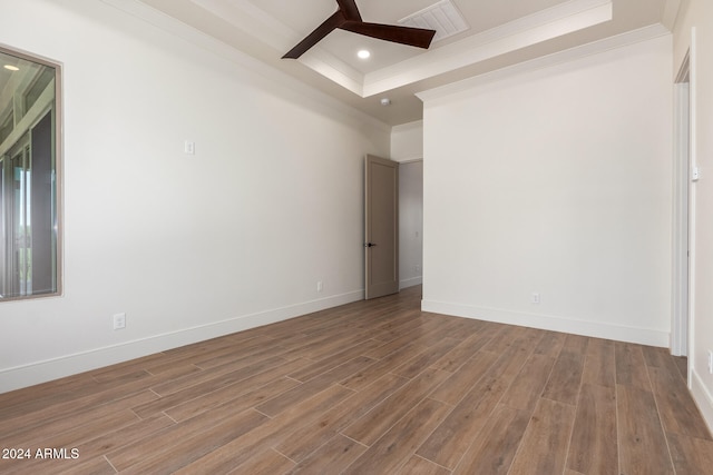 empty room featuring hardwood / wood-style floors, ceiling fan, and a tray ceiling