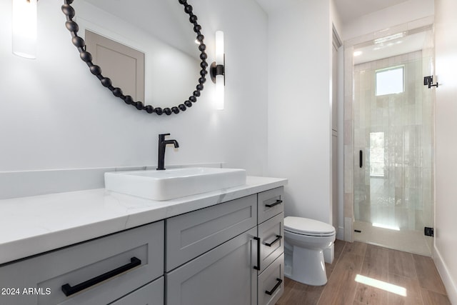 bathroom featuring hardwood / wood-style floors, vanity, toilet, and an enclosed shower