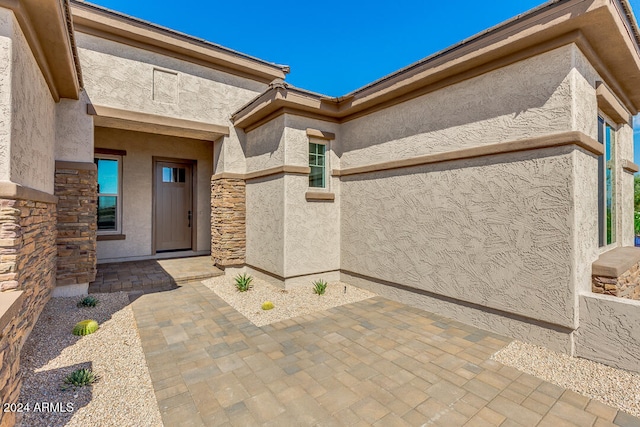 view of exterior entry with a patio