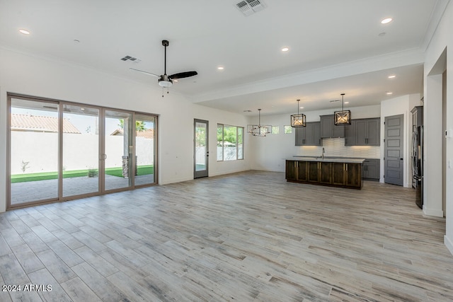 unfurnished living room featuring light wood-type flooring, ceiling fan, crown molding, and sink