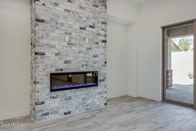 unfurnished living room featuring a brick fireplace, light hardwood / wood-style flooring, and ornamental molding