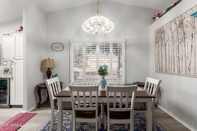 dining room featuring light wood-type flooring, lofted ceiling, and a notable chandelier