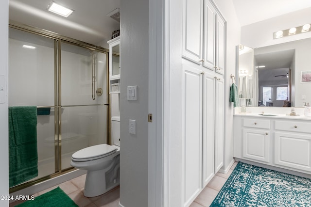 bathroom with toilet, vanity, tile patterned floors, and a shower with door