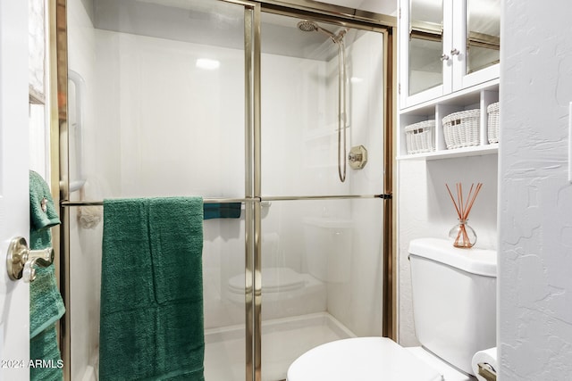 bathroom featuring a shower with door and toilet