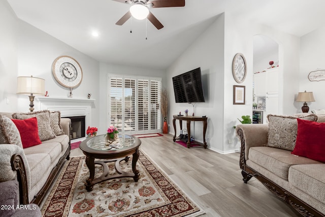 living room with light wood-type flooring, ceiling fan, and vaulted ceiling