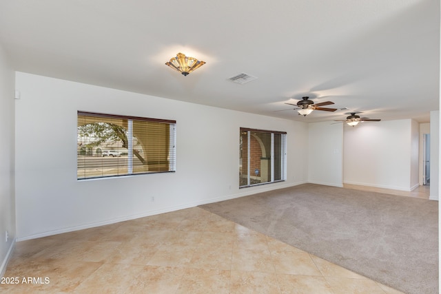 spare room featuring baseboards, carpet, visible vents, and tile patterned floors