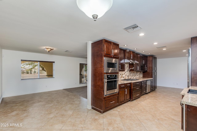 kitchen featuring under cabinet range hood, visible vents, appliances with stainless steel finishes, decorative backsplash, and light stone countertops