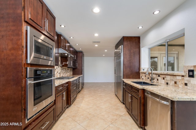 kitchen with light stone counters, visible vents, appliances with stainless steel finishes, a sink, and under cabinet range hood