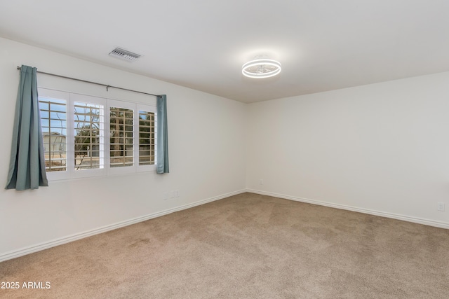 unfurnished room with carpet floors, visible vents, and baseboards