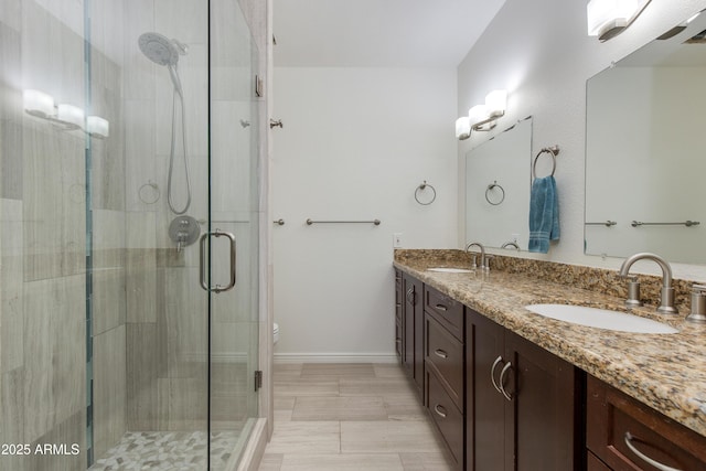 bathroom featuring a stall shower, a sink, and double vanity