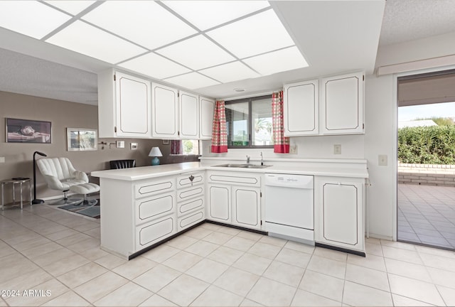 kitchen featuring dishwasher, sink, kitchen peninsula, light tile patterned floors, and white cabinetry