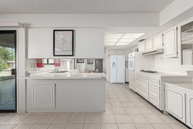 kitchen featuring sink, light tile patterned floors, kitchen peninsula, white appliances, and white cabinets