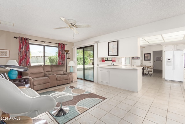 tiled living room with ceiling fan and a textured ceiling