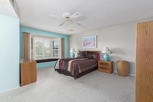 bedroom featuring ceiling fan, light colored carpet, and a textured ceiling