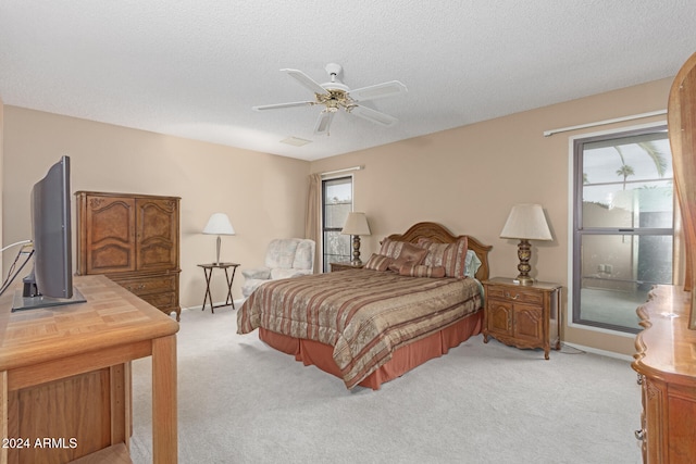 carpeted bedroom featuring ceiling fan and a textured ceiling