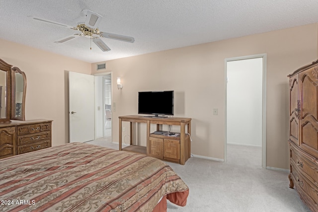 bedroom featuring ceiling fan, light colored carpet, and a textured ceiling