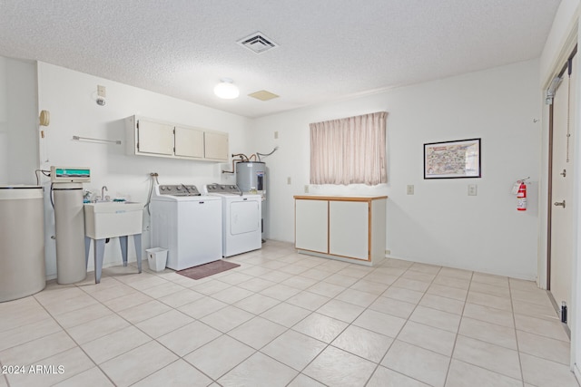 laundry room featuring washer and clothes dryer, cabinets, light tile patterned floors, and a textured ceiling