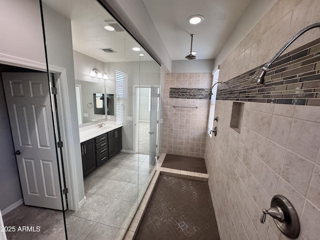 bathroom featuring vanity, a tile shower, and tile patterned floors