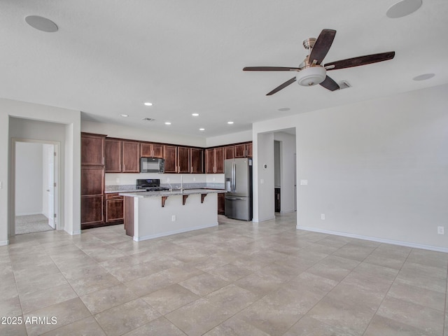 kitchen with a breakfast bar, a kitchen island with sink, range, ceiling fan, and stainless steel fridge with ice dispenser