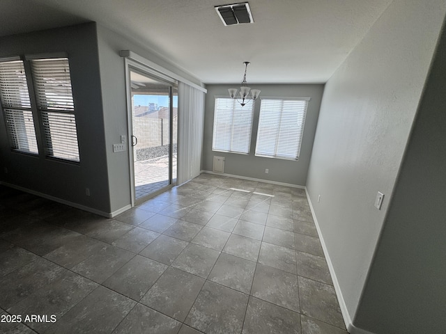 unfurnished dining area featuring a notable chandelier and dark tile patterned flooring