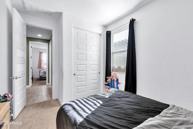 carpeted bedroom with multiple windows and a closet