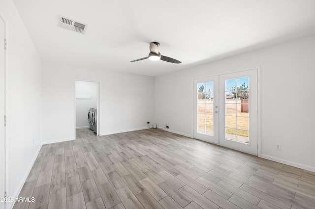 spare room with light hardwood / wood-style floors, french doors, washer and dryer, and ceiling fan