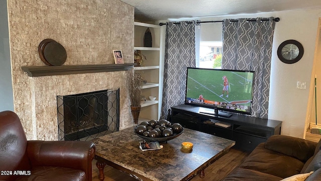 living room featuring a textured ceiling, a stone fireplace, and hardwood / wood-style flooring