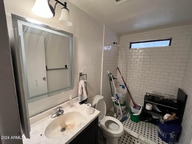 bathroom featuring toilet, a textured ceiling, vanity, tile walls, and tile flooring