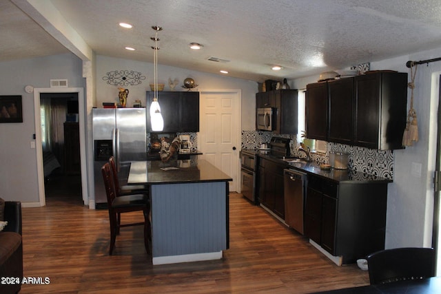 kitchen featuring decorative light fixtures, a breakfast bar, stainless steel appliances, lofted ceiling with beams, and dark hardwood / wood-style flooring