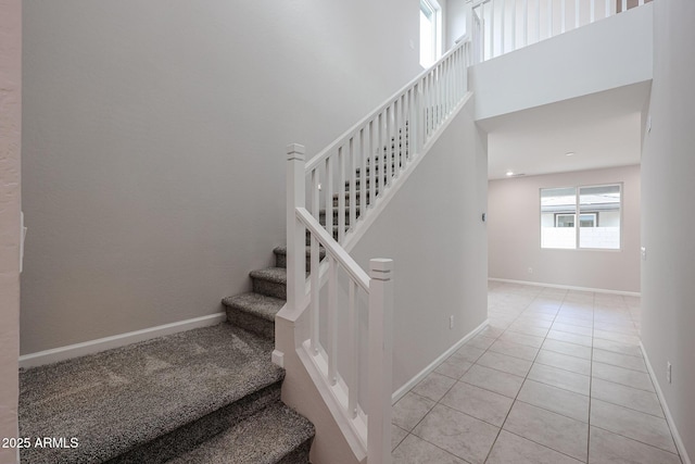 stairs featuring tile patterned flooring and a high ceiling