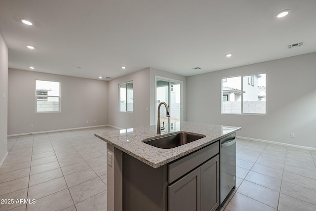 kitchen with dishwasher, a center island with sink, sink, light stone countertops, and a wealth of natural light