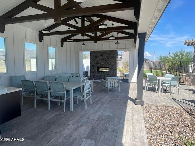 view of patio / terrace with a ceiling fan, outdoor dining area, an outdoor living space with a fireplace, a gazebo, and fence