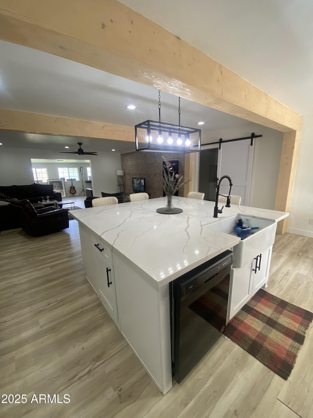 7201 N 16th Dr, Phoenix, AZ 85021 - kitchen featuring a barn door, dishwasher, a center island with sink, light wood-type flooring, and white cabinets
