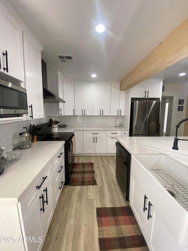 7201 N 16th Dr, Phoenix, AZ 85021 - kitchen with appliances with stainless steel finishes, wall chimney exhaust hood, light wood-style flooring, white cabinetry, and recessed lighting