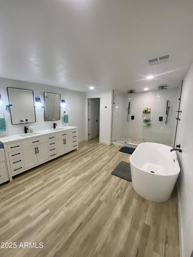 7201 N 16th Dr, Phoenix, AZ 85021 - bathroom featuring a stall shower, double vanity, wood finished floors, a freestanding tub, and baseboards