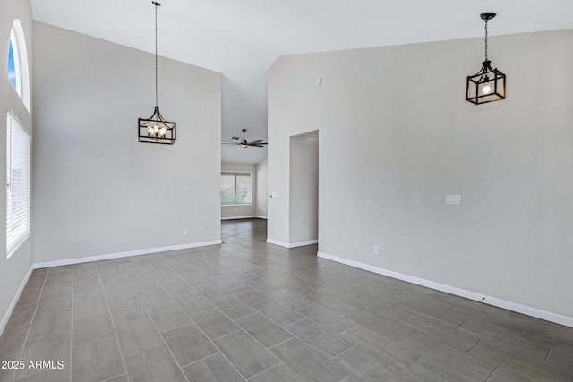 interior space with high vaulted ceiling, ceiling fan with notable chandelier, and baseboards