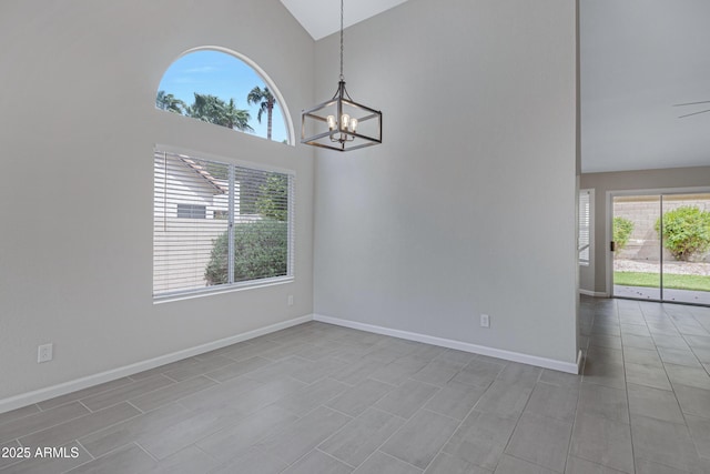 empty room with high vaulted ceiling, a notable chandelier, and baseboards