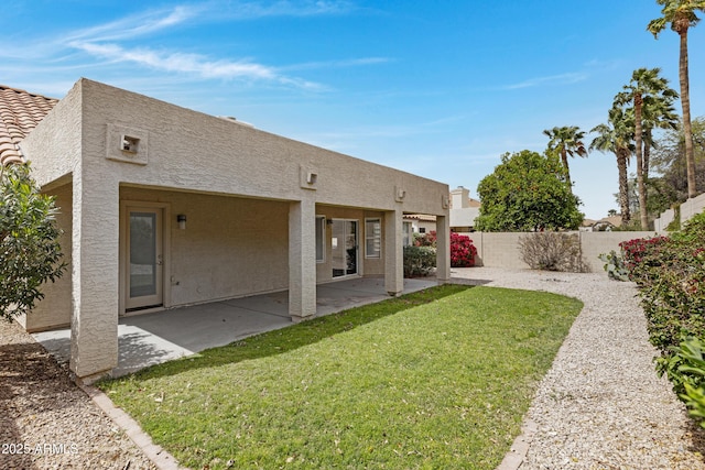 back of property featuring a yard, a fenced backyard, stucco siding, and a patio area