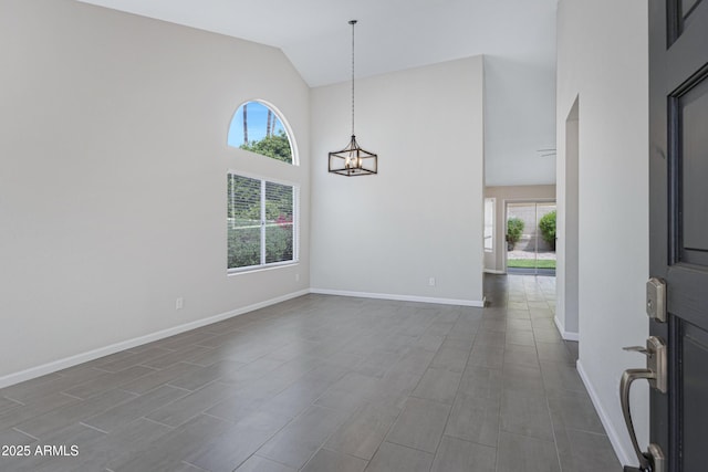 spare room featuring baseboards, high vaulted ceiling, and a notable chandelier