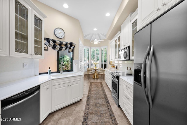 kitchen featuring glass insert cabinets, recessed lighting, white cabinetry, a sink, and appliances with stainless steel finishes