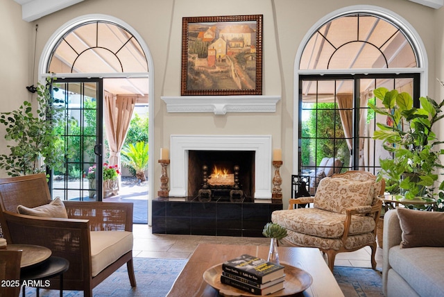 tiled living area featuring plenty of natural light and a warm lit fireplace