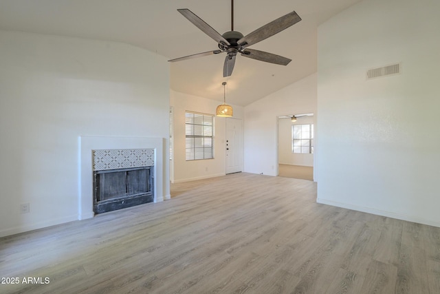 unfurnished living room with light wood-type flooring, visible vents, a wealth of natural light, and a tile fireplace