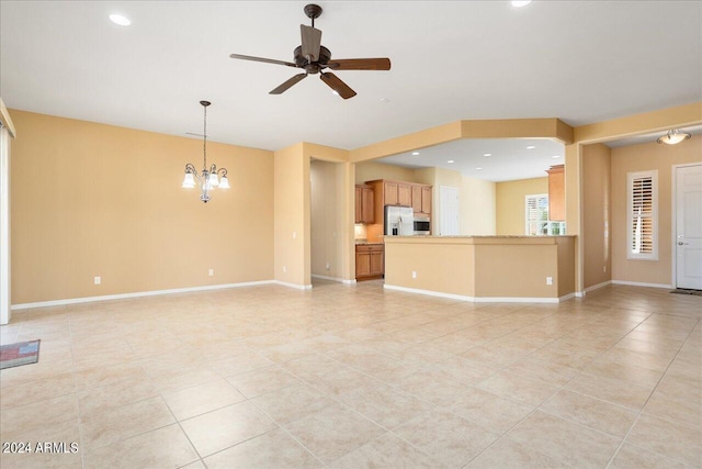 unfurnished living room with ceiling fan with notable chandelier and light tile patterned floors