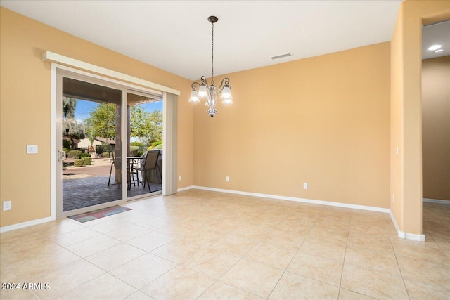 empty room with an inviting chandelier and light tile patterned floors