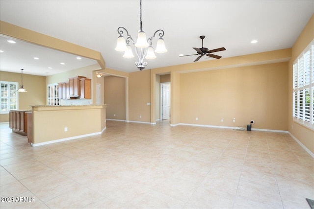 unfurnished living room with a wealth of natural light, ceiling fan with notable chandelier, and light tile patterned flooring